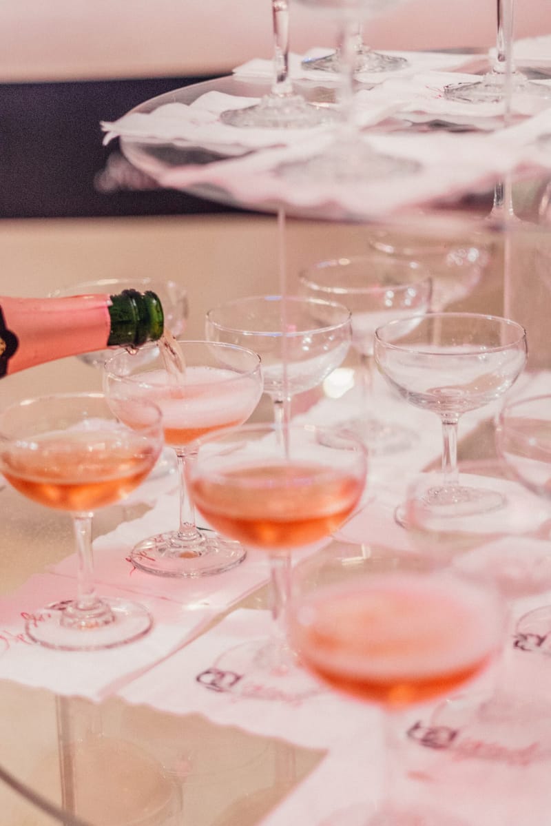 Rosé champagne being poured into a coupe tower set on printed logo napkins