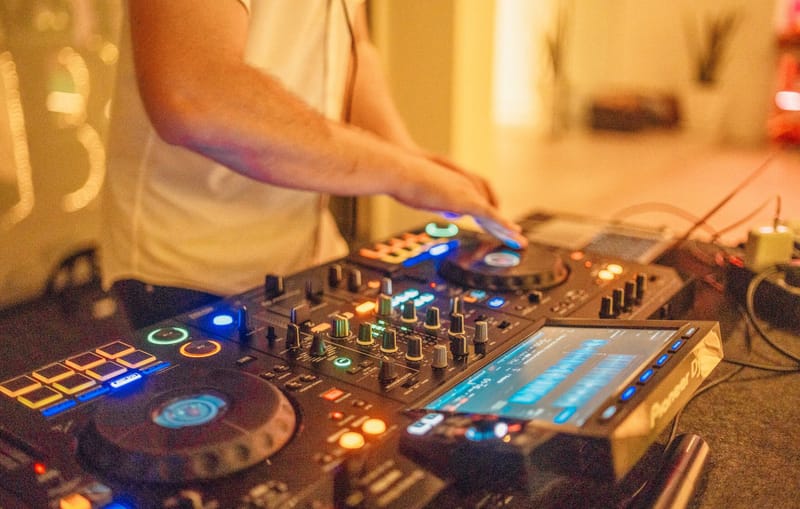 Close-up of a DJ's hands on a lit mixing controller