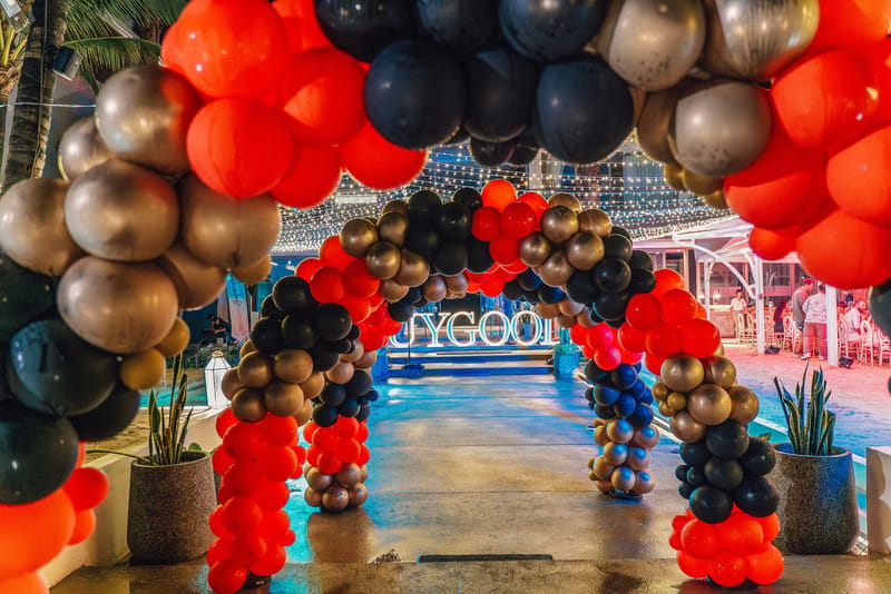 Red, black, gold and blue balloon tunnel leading to BUYGOODS marquee letters