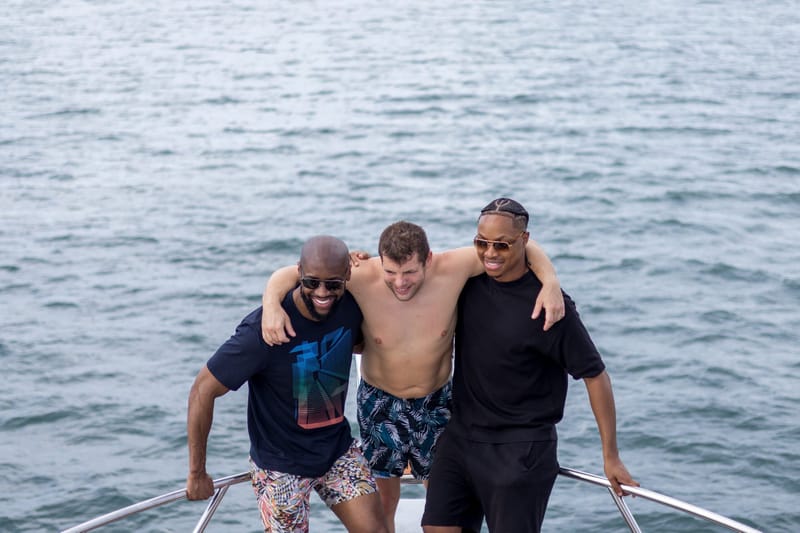 Three men posing on the bow of a boat