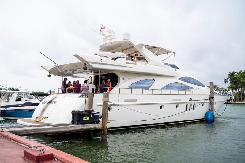 White yacht docked at a pier with guests on its decks