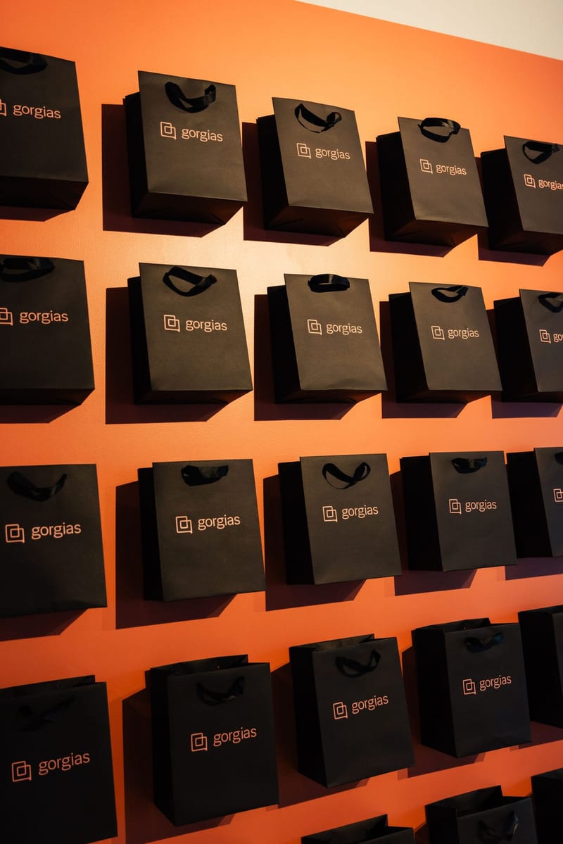 Orange wall hung with rows of black Gorgias gift bags
