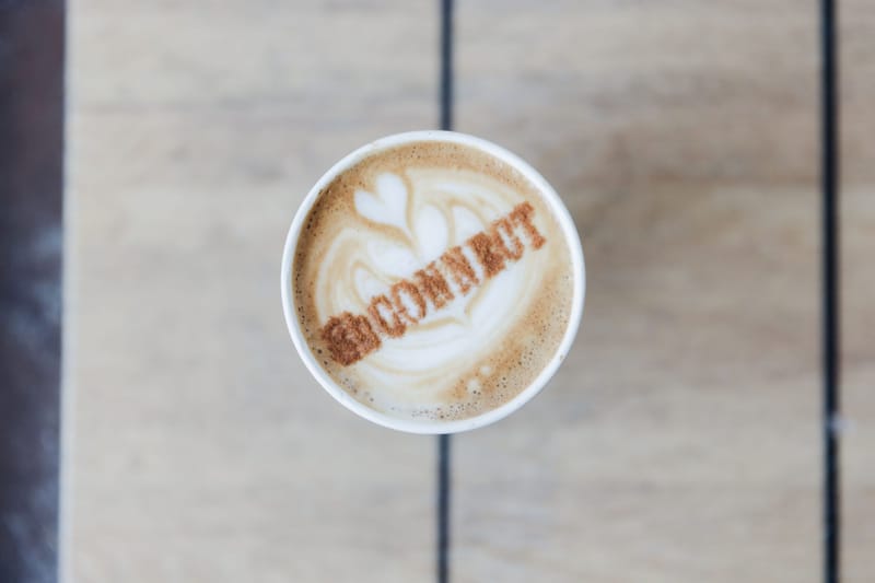 Latte in a white cup with the word Connect dusted onto the foam