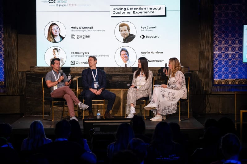 Four panelists seated on stage under a slide reading Driving Retention through Customer Experience