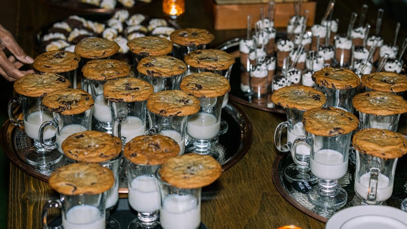 Chocolate chip cookies balanced on top of glasses of milk