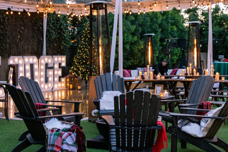 Black Adirondack chairs with plaid and white throws around a fire pit near SKI LODGE letters