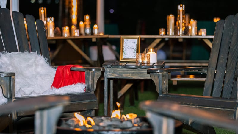 Adirondack chairs with faux fur and red throws around a fire pit and a small framed sign