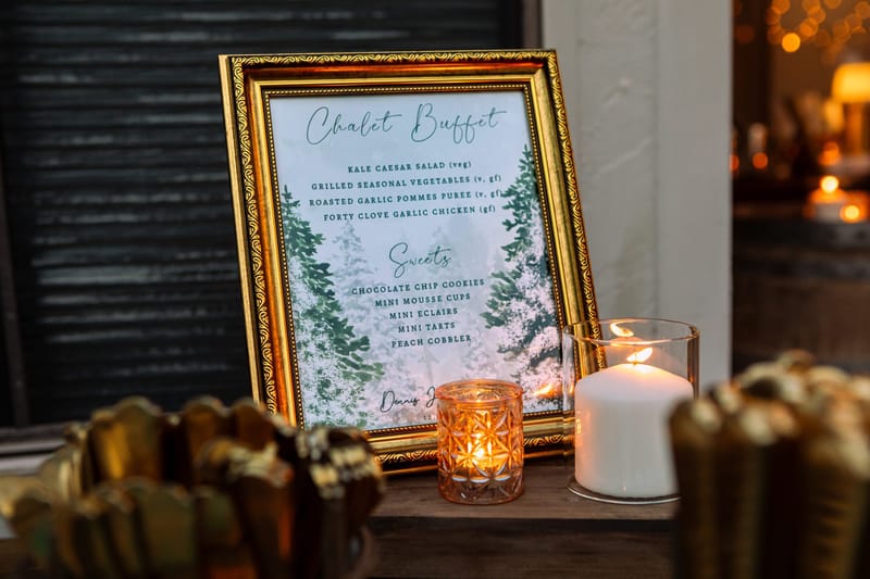 Gold framed Chalet Buffet menu listing dinner and sweets beside a lit candle