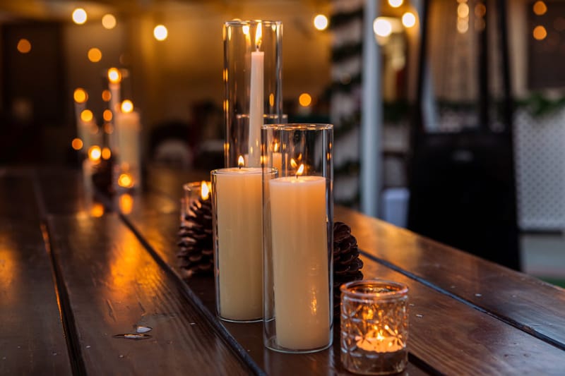 Tall pillar candles in glass holders glowing along a wooden table