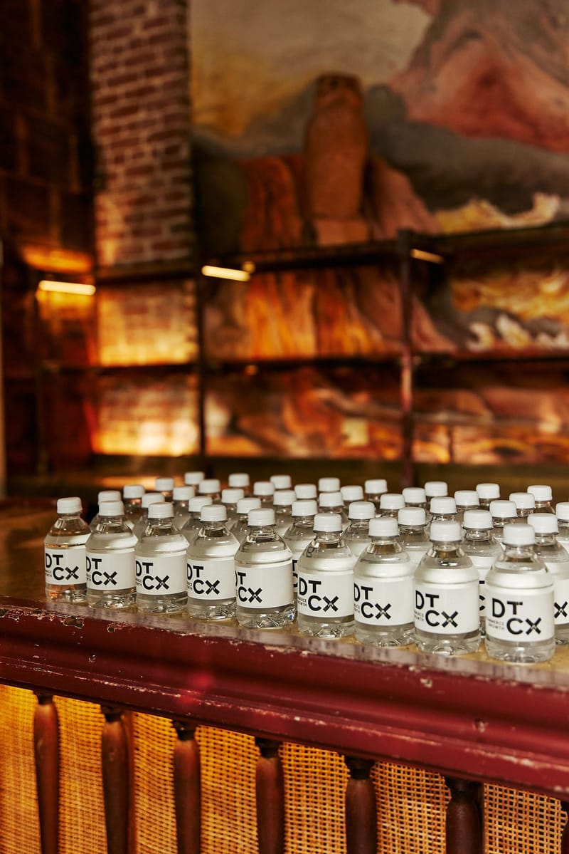 Rows of water bottles labeled DT CX lined up along a bar counter