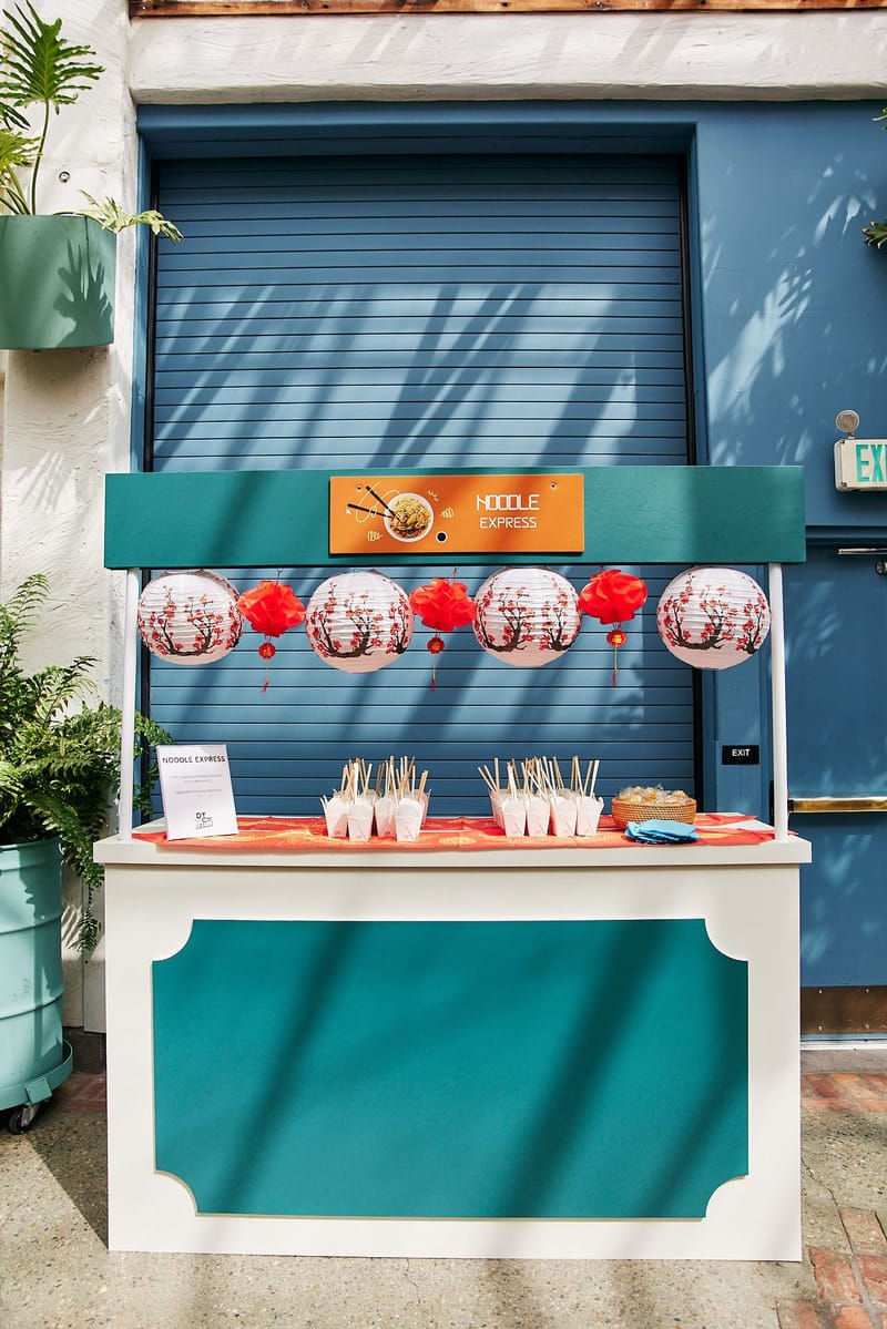 Noodle Express cart with paper lanterns and takeout boxes of noodles with chopsticks