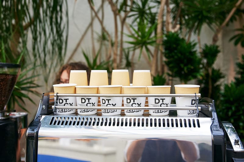 Stacked DTCx Retain paper coffee cups on top of an espresso machine