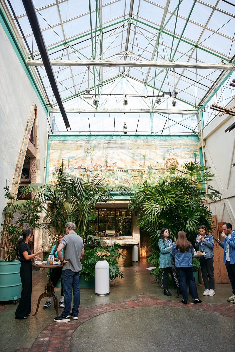 Guests talking under a glass roof among potted palms