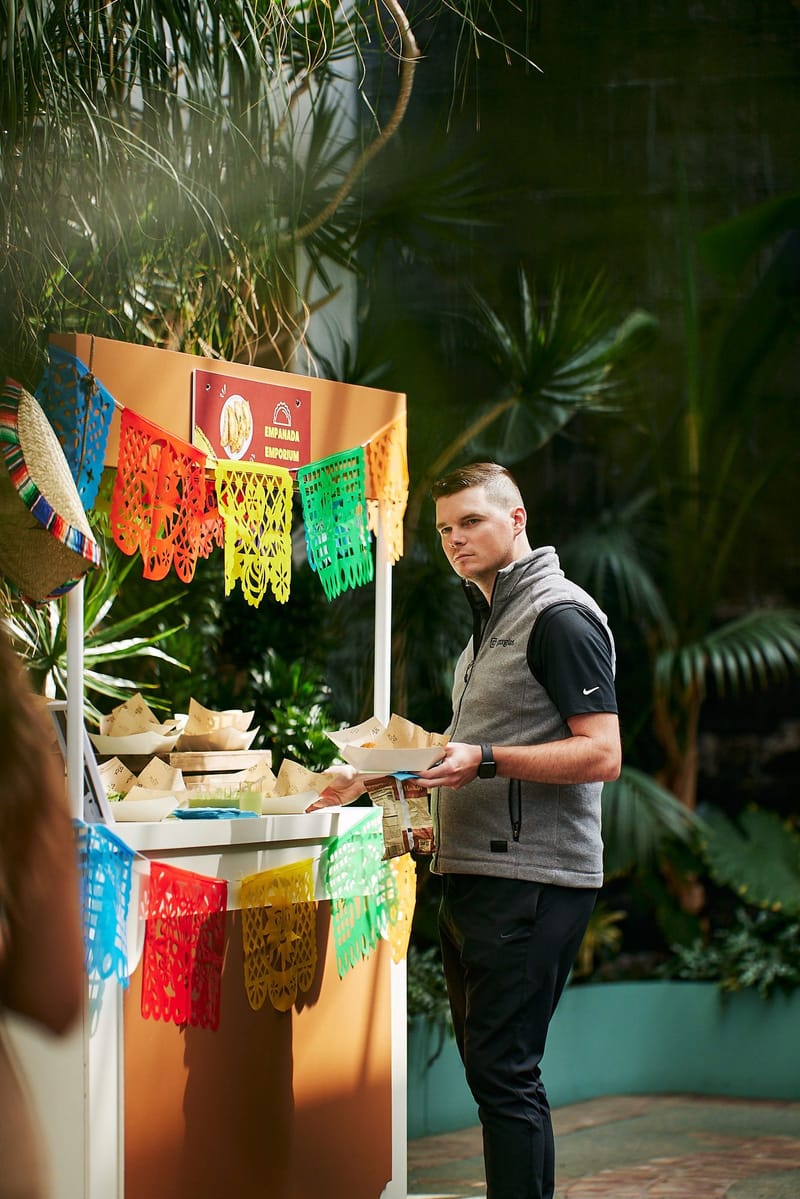 Empanada Emporium stand hung with colorful cut paper banners, with a guest in a Gorgias vest