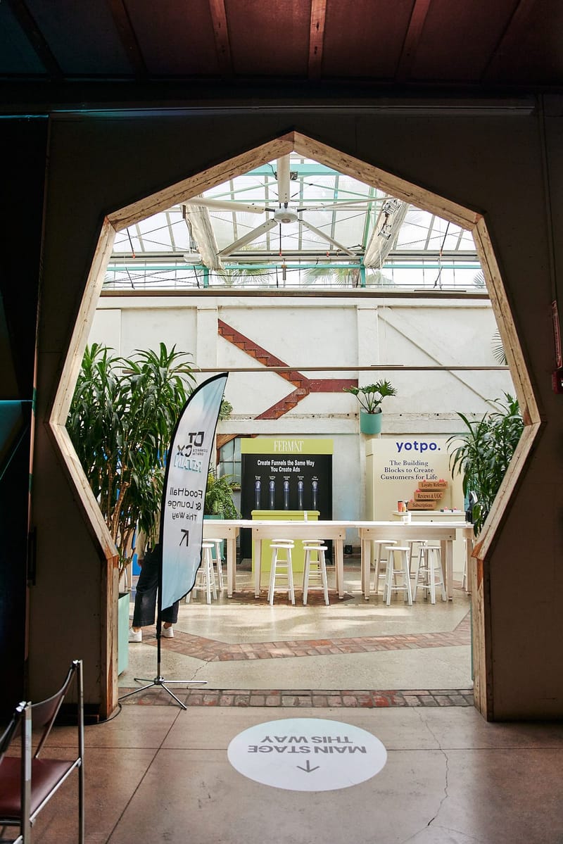 Angled doorway framing the FERMÀT and Yotpo spaces, beside a Food Hall & Lounge This Way flag