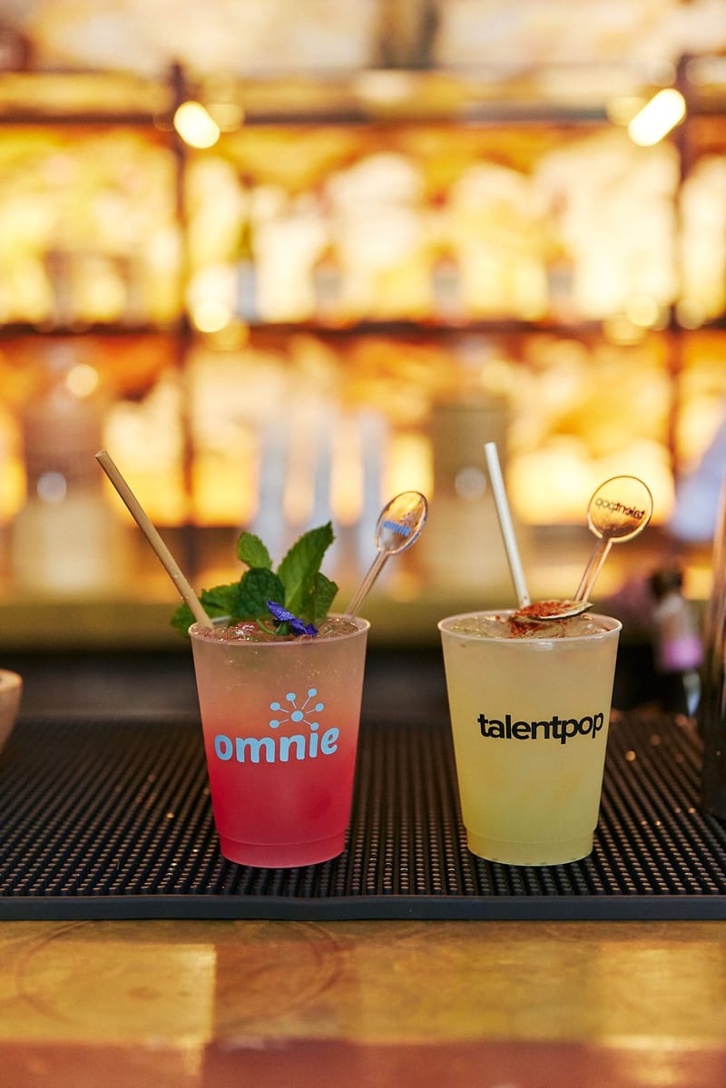 Omnie and talentpop cups of garnished drinks on a bar mat