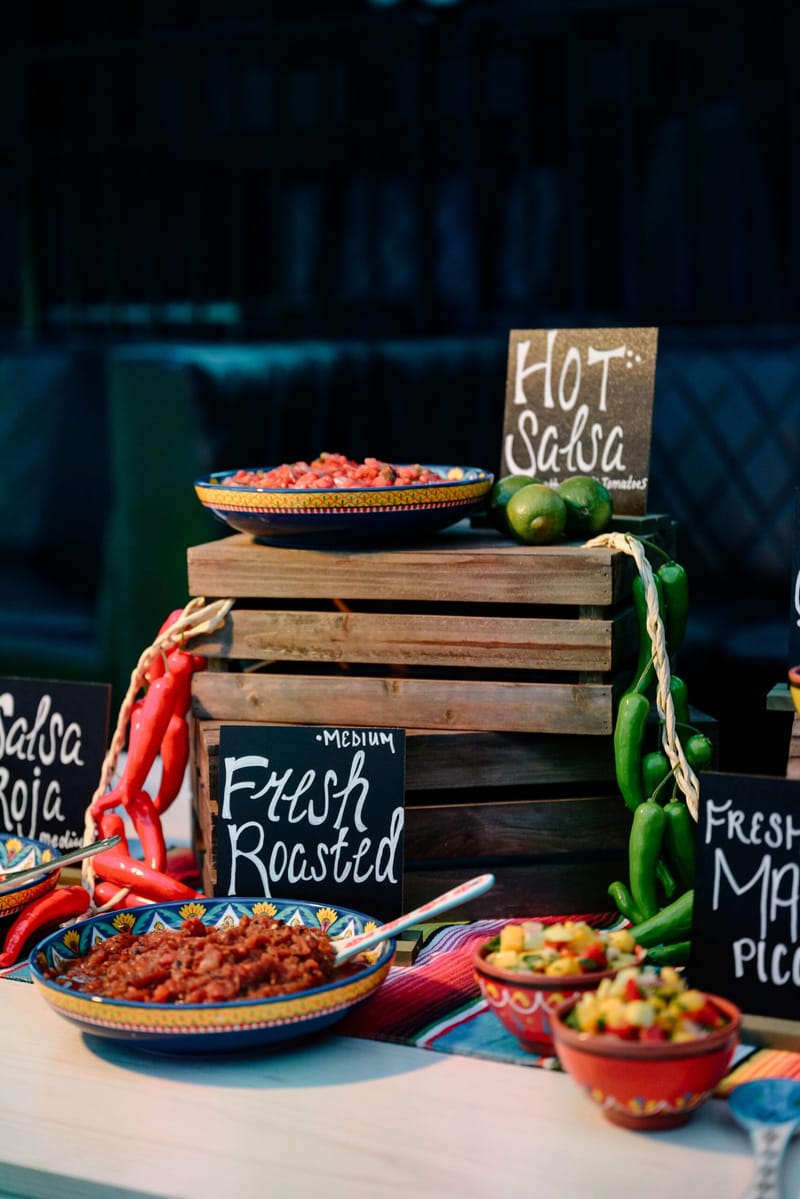 Salsa bar with hand-lettered Hot Salsa and Fresh Roasted signs, wooden crates and strings of chiles
