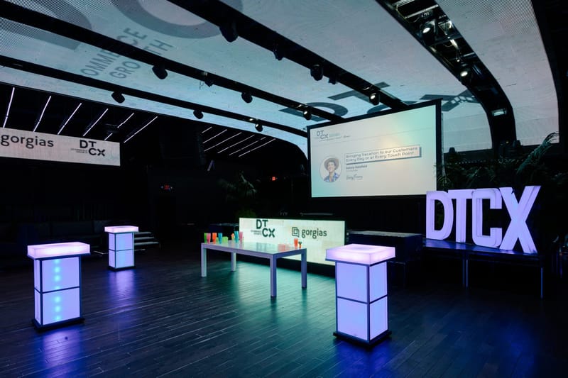 Stage with DTCX letters, glowing cube tables and colorful cups in front of a DTCX and gorgias panel