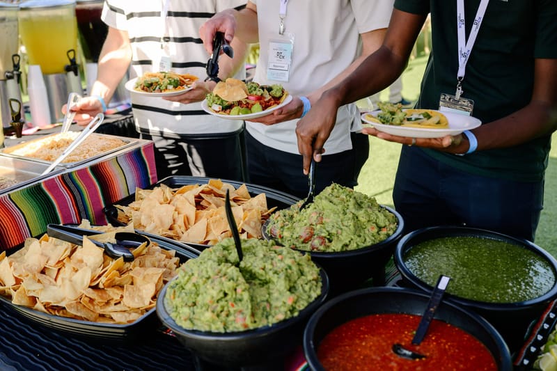 Guests serving themselves chips, guacamole and salsa from black bowls