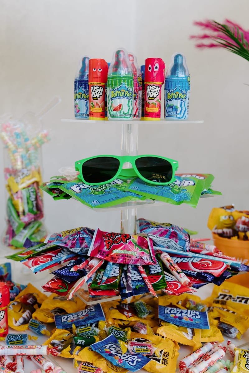Acrylic candy stand with Baby Bottle Pops and Push Pops above green sunglasses on Fun Dip packets