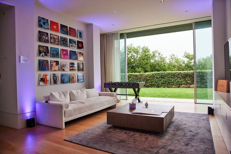 Living room with a white sofa, a grid of colorful framed squares and open glass doors to a lawn