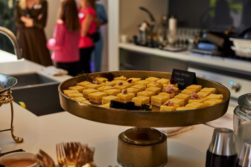 Gold tray of mini Meyer lemon bars with a chalkboard label
