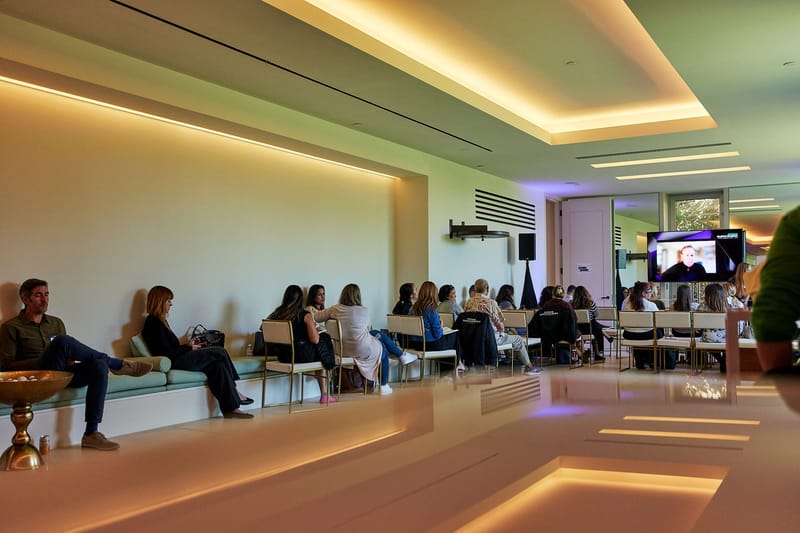 Guests on long built-in benches watching a screen in a room with glowing cove lighting