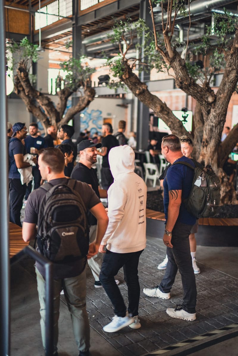Attendees talking in groups beneath trees growing inside the hall