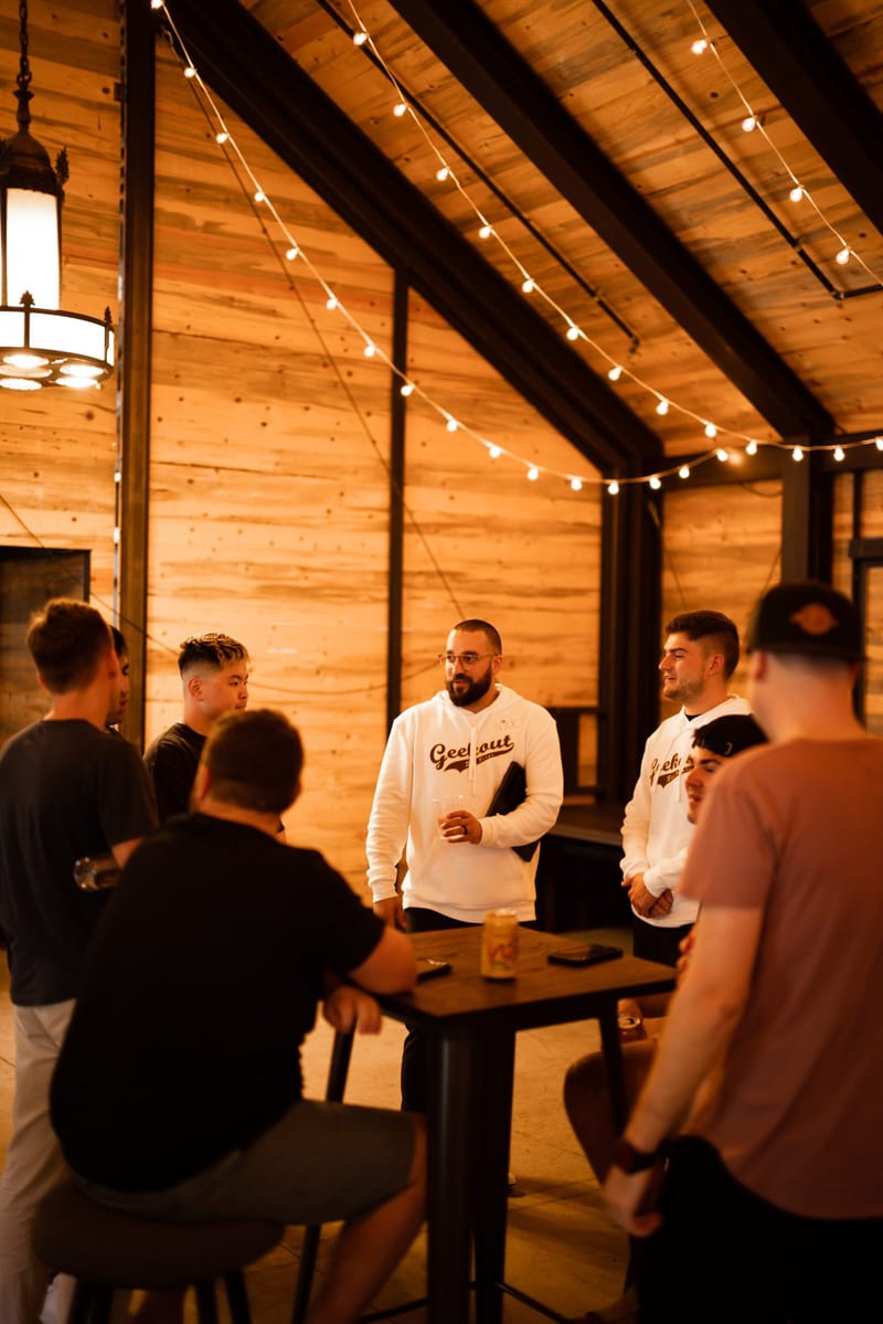 Guests around a high table in a wood-panelled room with string lights along the ceiling