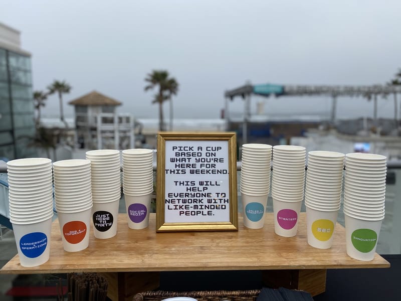 Framed Pick a cup sign between stacks of cups labeled SEO, Strategy, Social Media and Just Here To Party