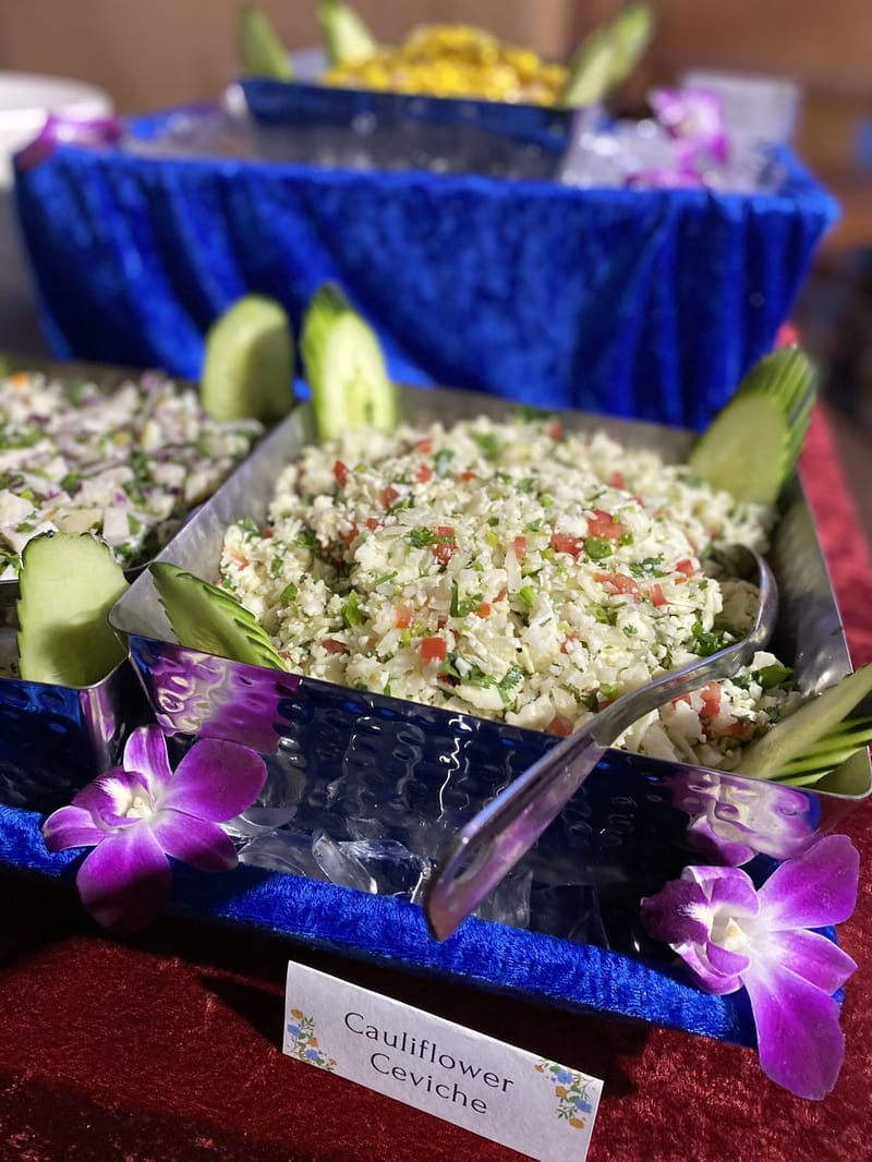 Cauliflower Ceviche with a name card on a blue velvet display decorated with purple orchids