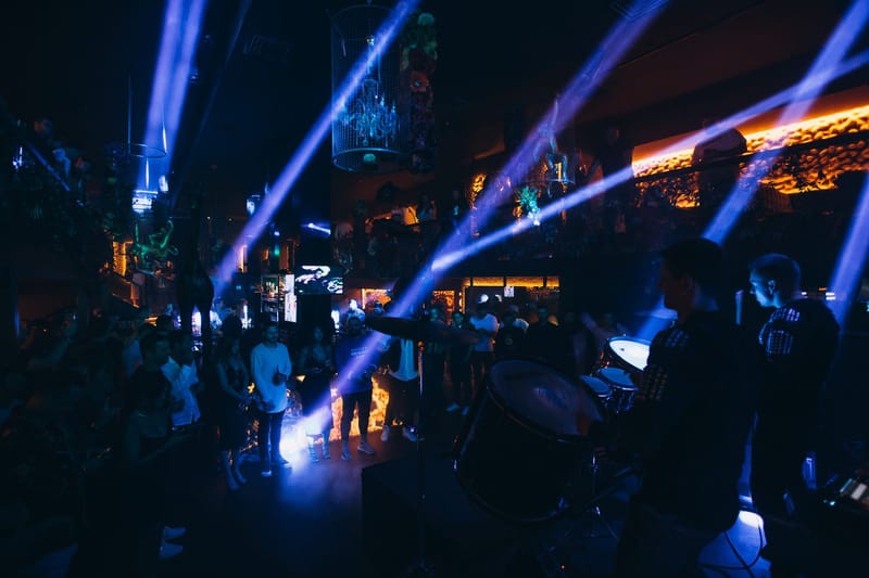 Blue light beams sweeping over a crowd while a drummer plays in the foreground