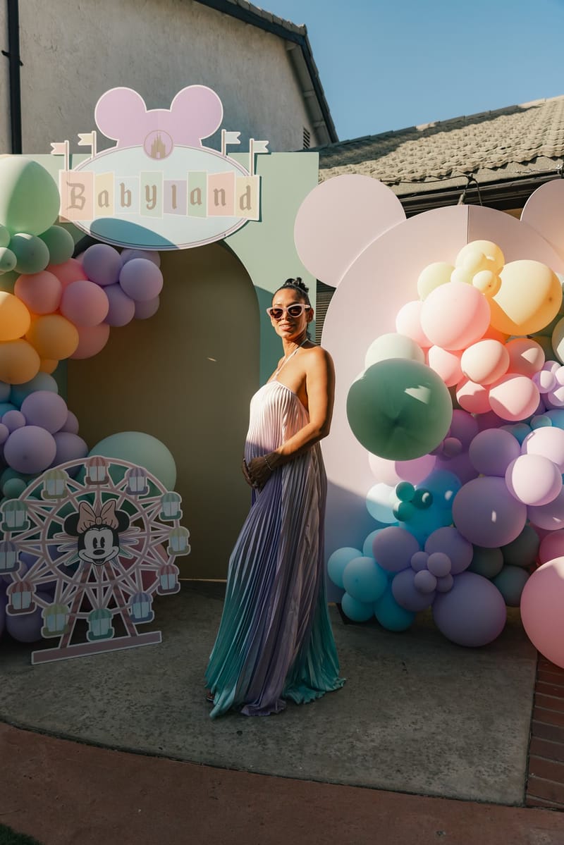 Jeaneth in a pastel pleated gown posing in front of the Babyland balloon arch