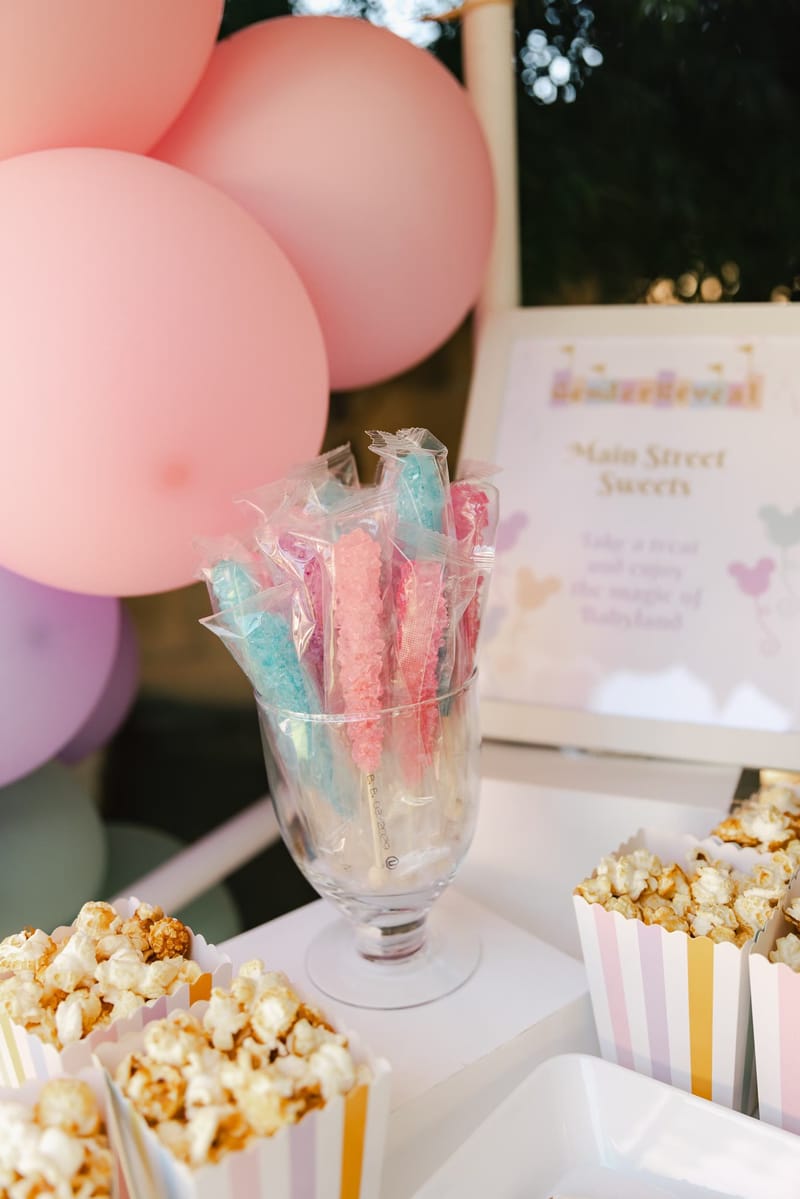Striped popcorn boxes and rock candy sticks in front of a Main Street Sweets sign