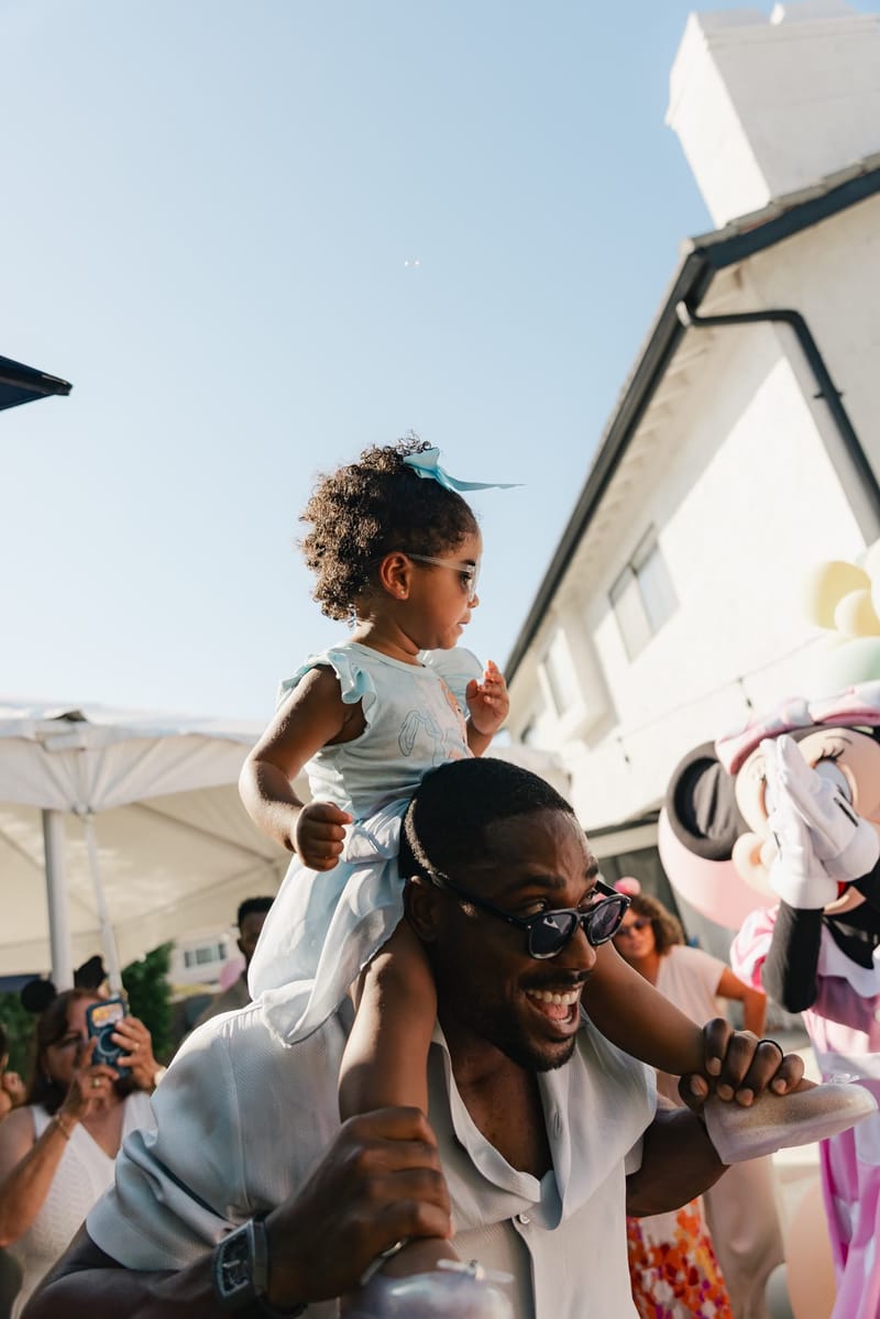 A little girl riding on a man's shoulders at the party