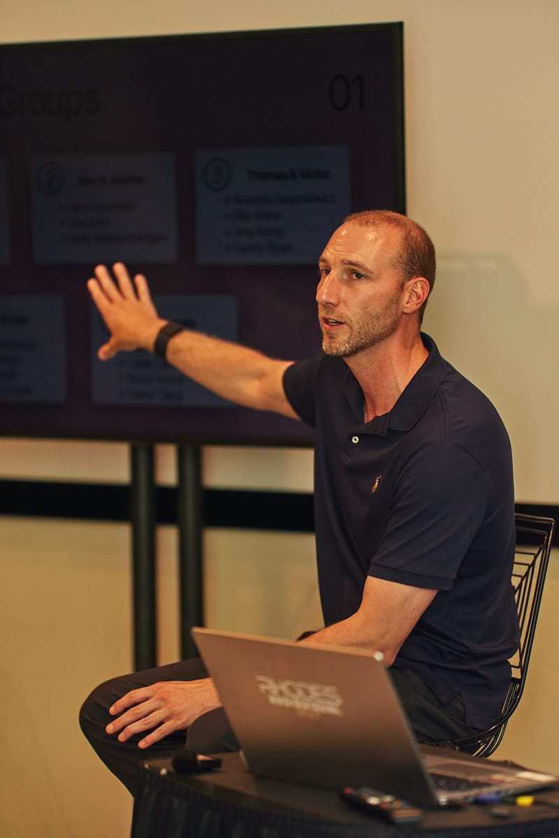 A seated speaker with a laptop gesturing toward a screen titled Groups