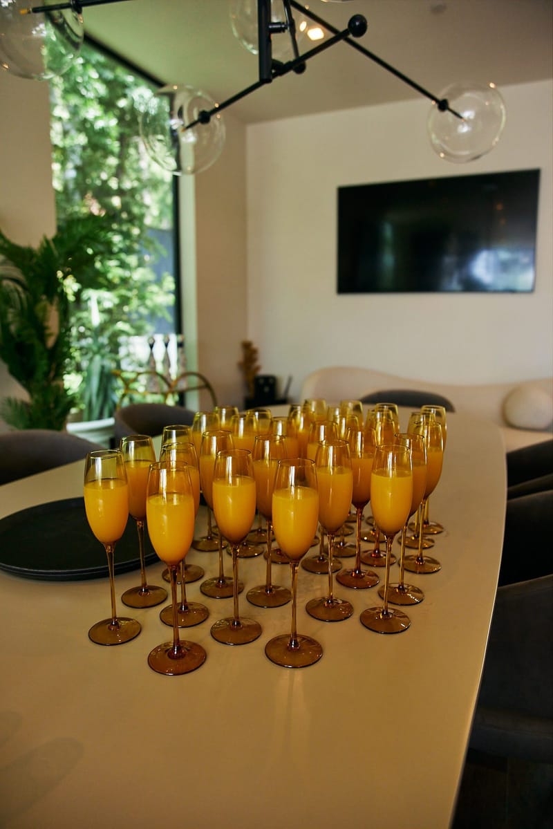 Rows of mimosas in tall flutes on a white counter