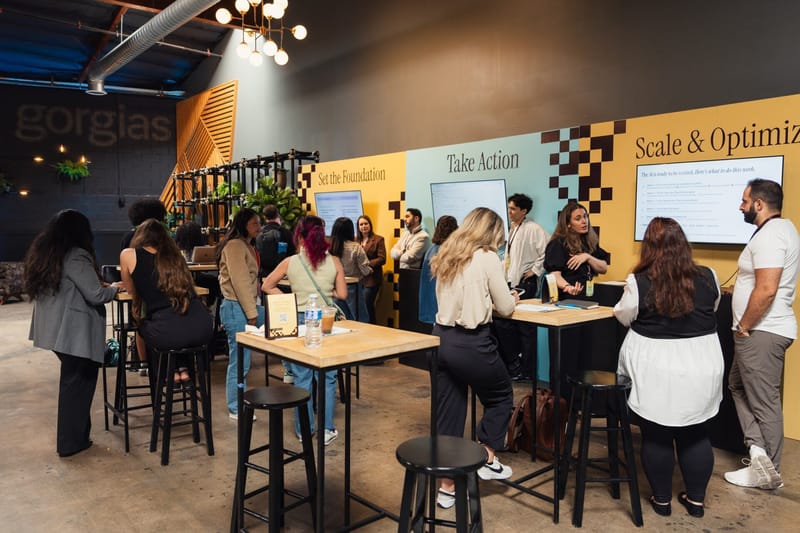 Guests at high-top tables in front of color-blocked Gorgias walls and presentation screens