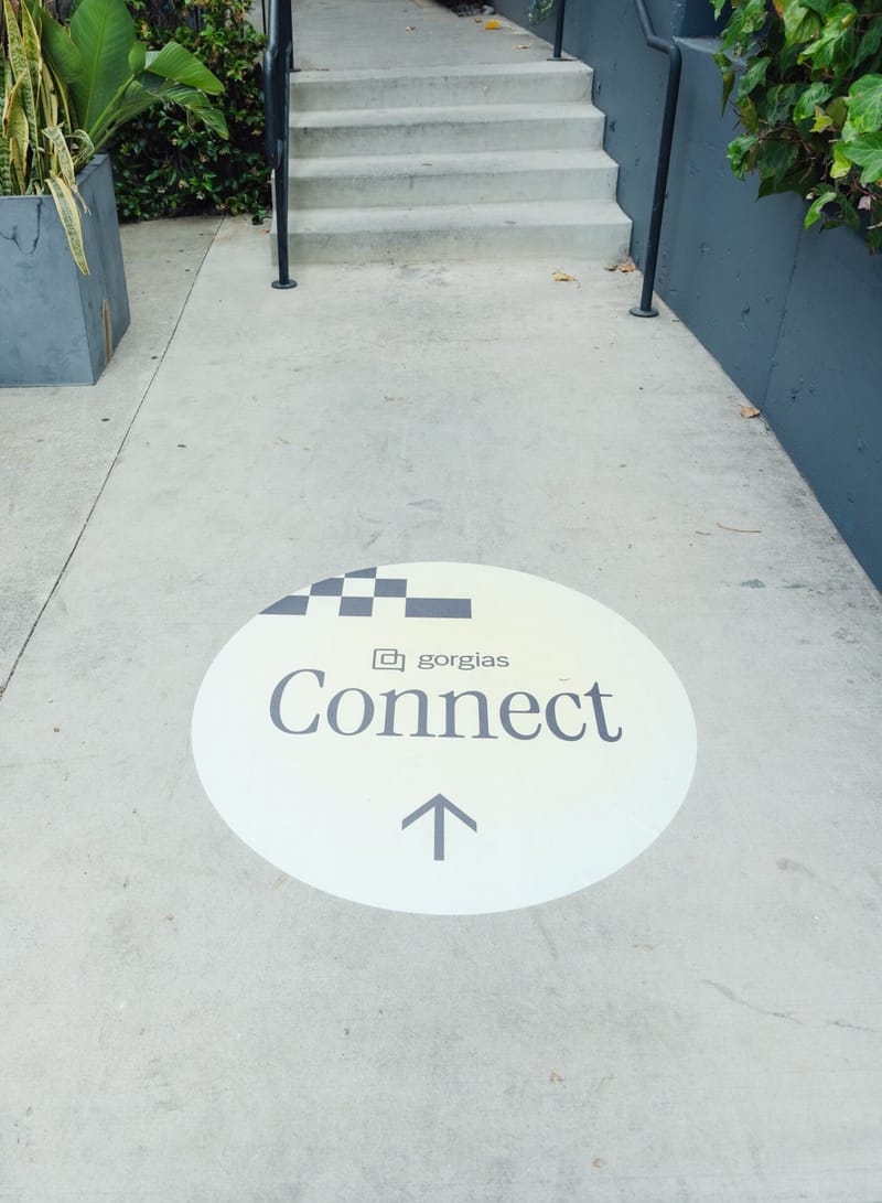 Round Gorgias Connect floor decal with an arrow at the foot of a set of outdoor steps