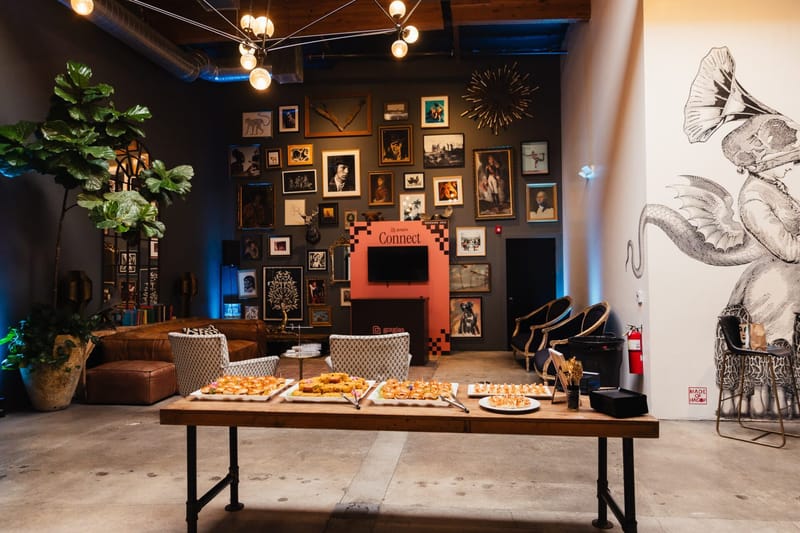 Lounge with leather sofas and a table of food in front of a wall of framed pictures and the coral Connect kiosk