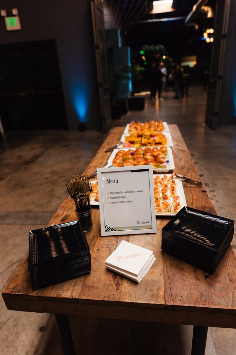 Long wooden table set with trays of food and a menu card