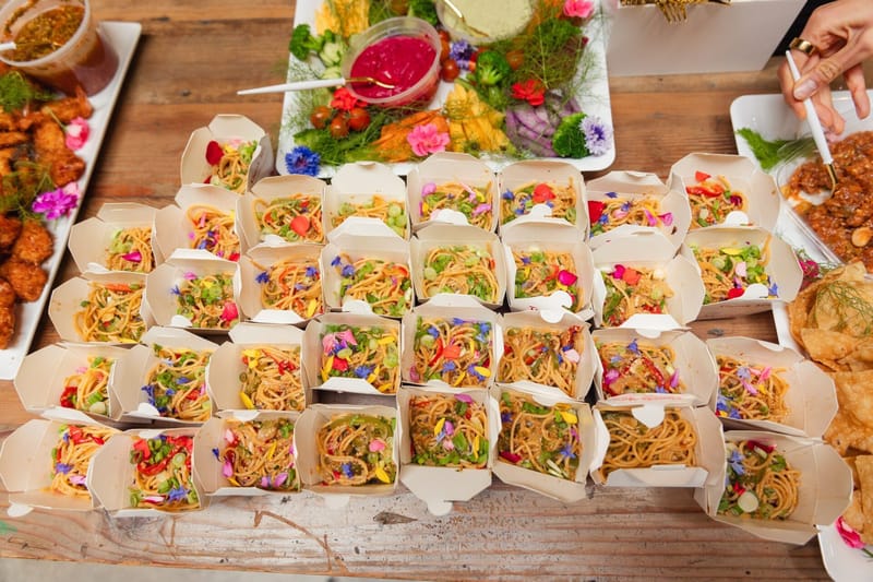 Catering boxes of noodles topped with edible flowers