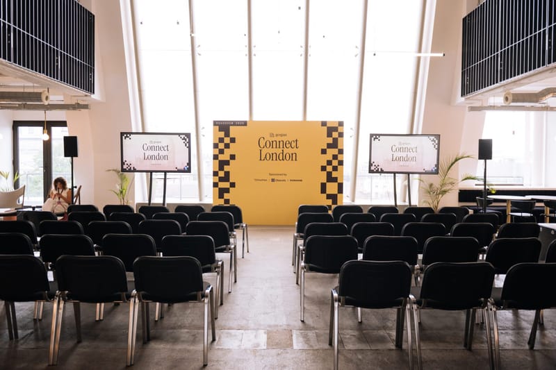 Classroom-style rows of black chairs facing a yellow and black Gorgias Connect London backdrop between two screens