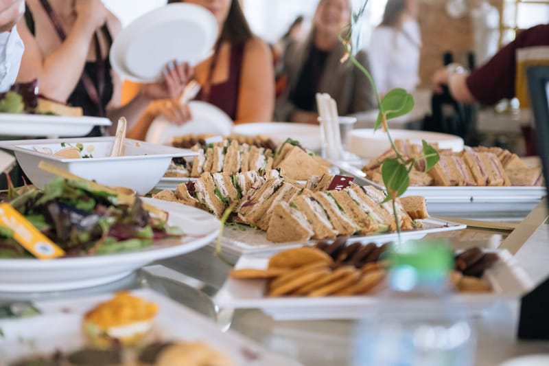 Guests serving themselves sandwiches, salad and cookies from a buffet