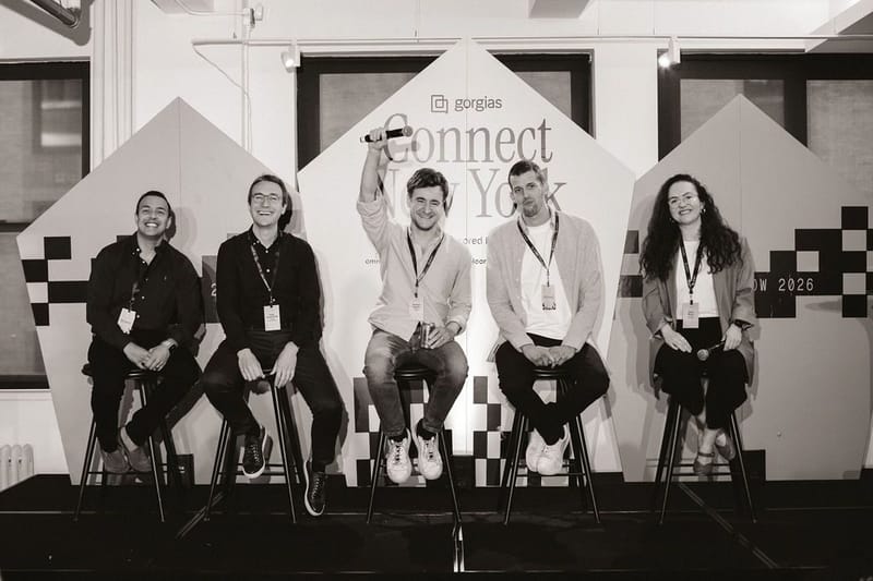 Five panelists on stools in front of the checkered Connect New York panels, in black and white
