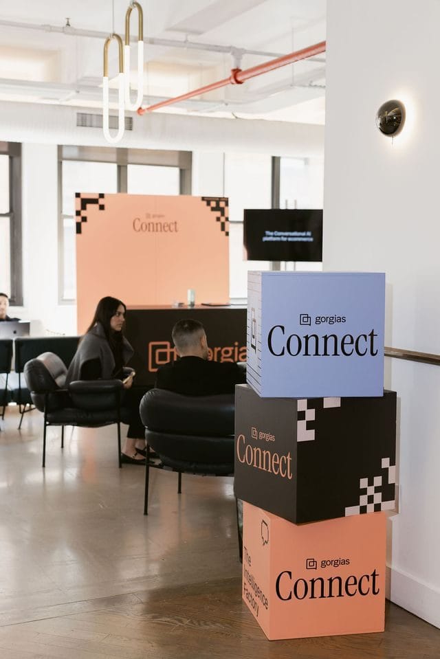 Blue, black and coral Connect cubes stacked near lounge chairs, with a coral Connect backdrop behind