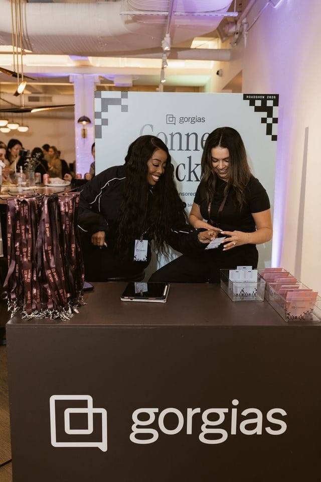 Two people behind a brown Gorgias check-in counter in front of a Connect backdrop
