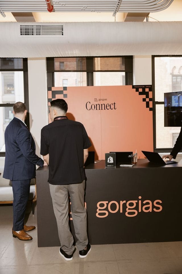 Two guests talking at a black Gorgias counter in front of a coral Connect backdrop