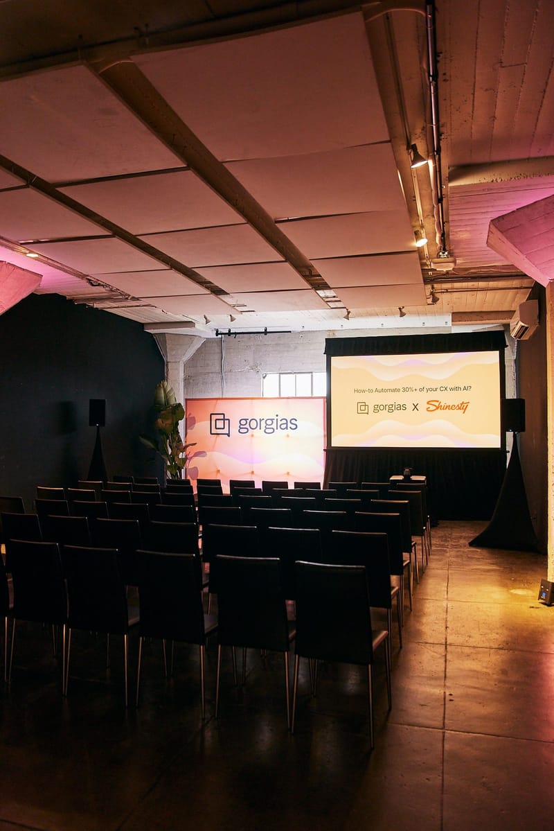 Breakout room with black chairs, a Gorgias banner and a screen reading gorgias x Shinesty