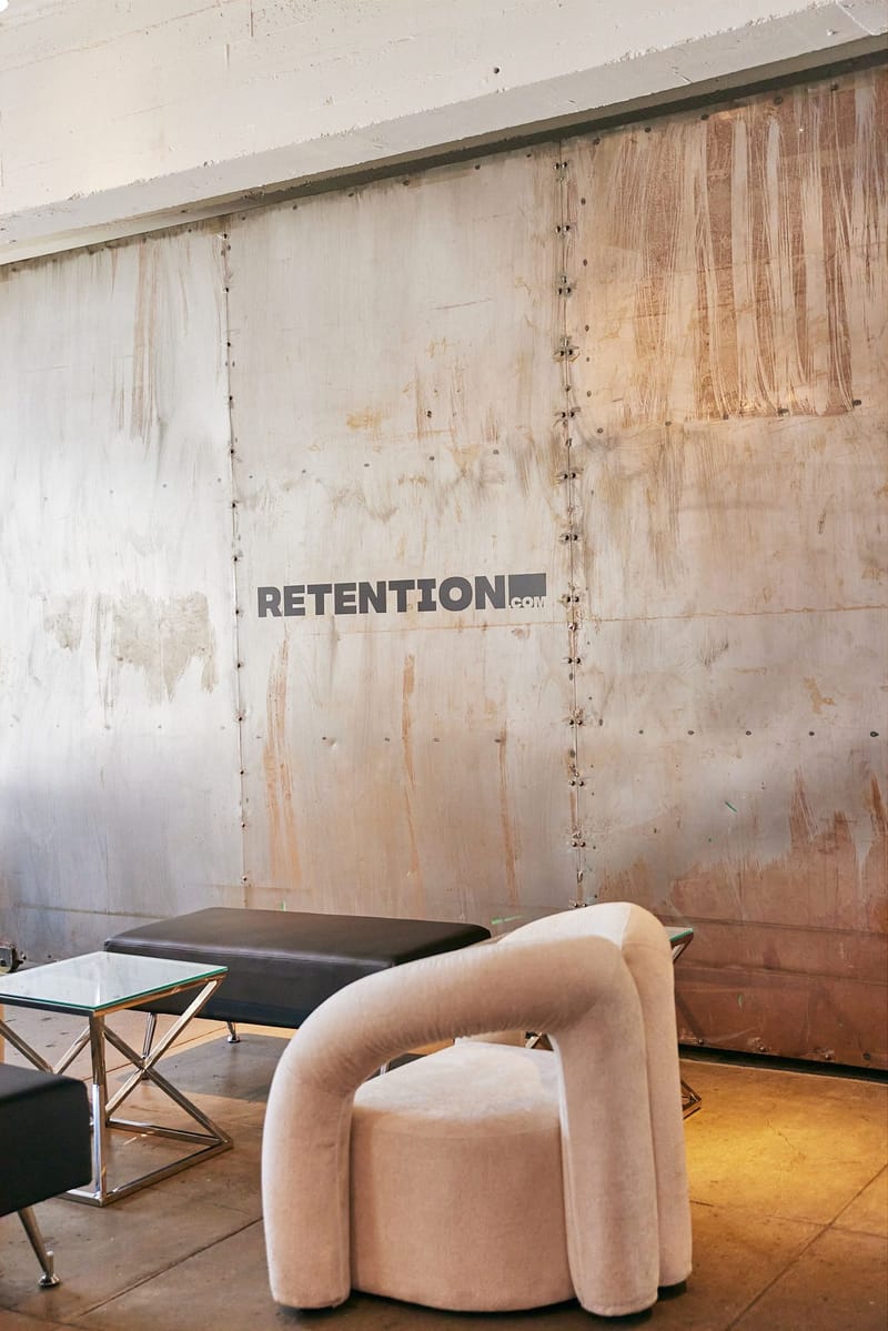 Retention.com logo on a metal wall beside a lounge chair